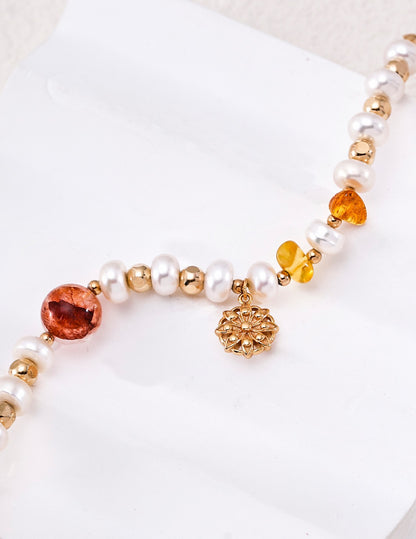 Close-up of freshwater pearls, amber crystals, and floral charm