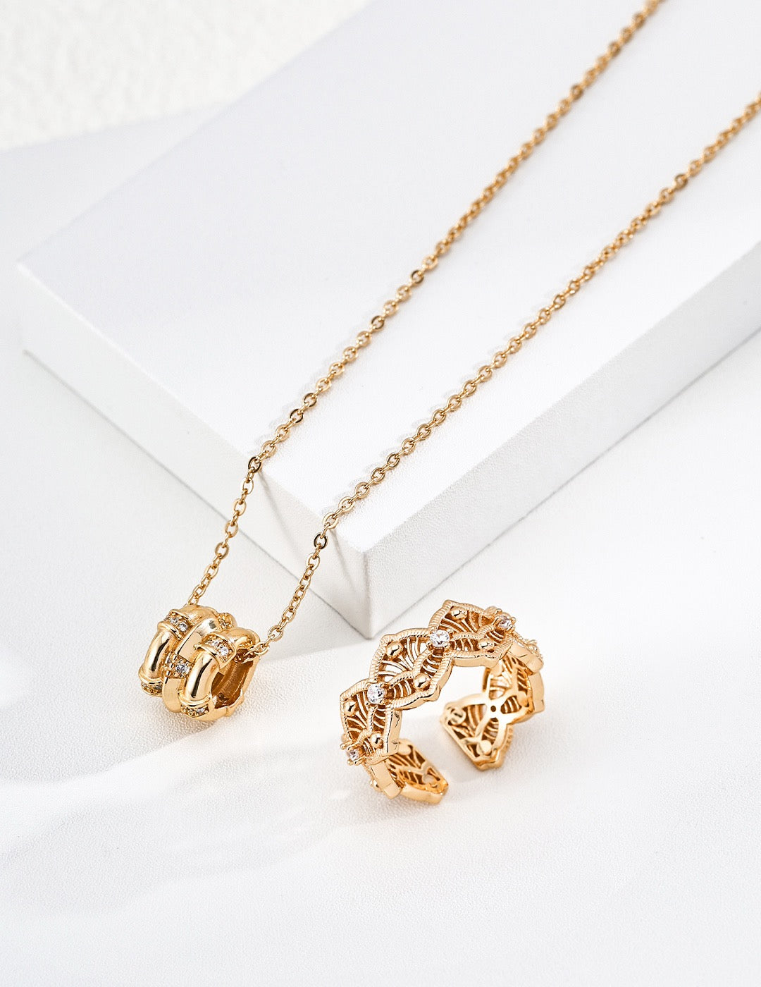 Astra gold pendant necklace beside matching sculptural jewelry