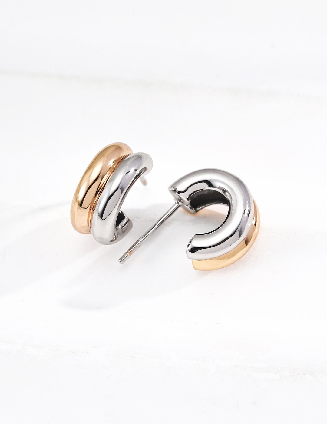 Gold Trinité huggie earrings styled with a pendant necklace
